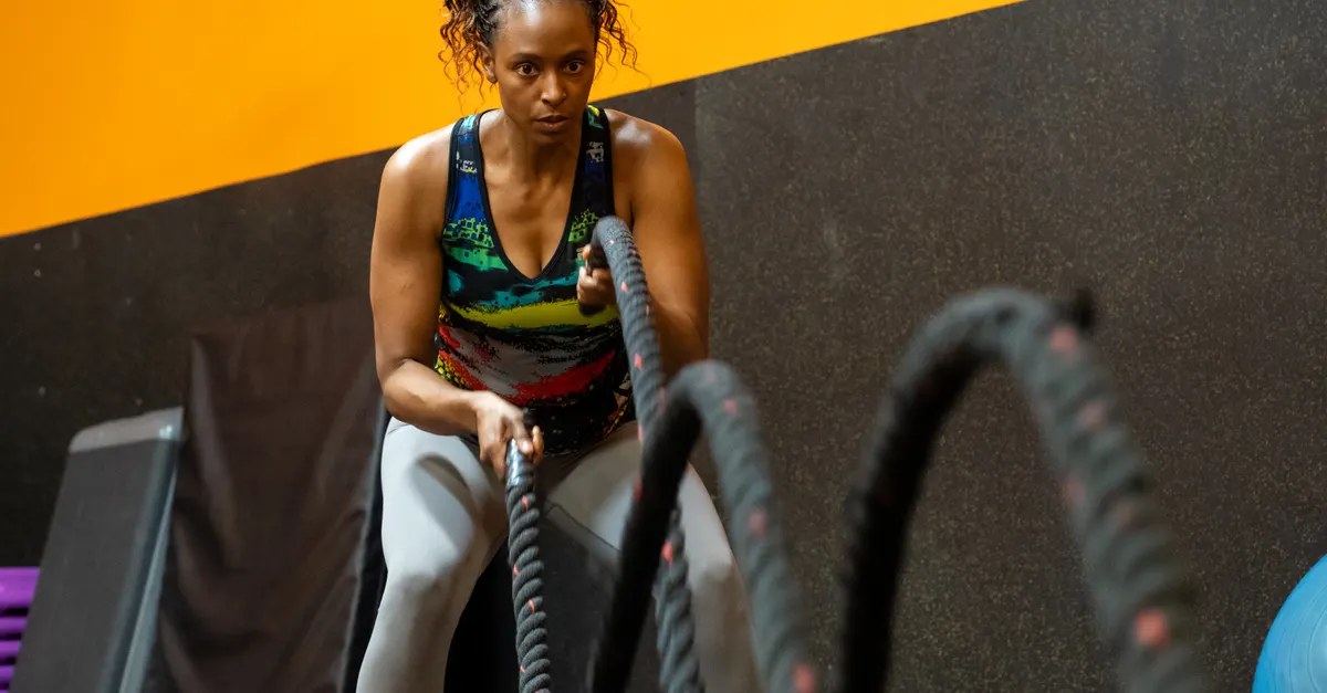 Woman training hard with battle ropes in a cardio workout